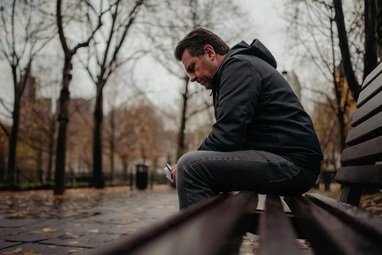 Грустный мужчина сидит на лавочке